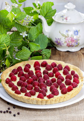 Raspberry tart on wooden table, vintage kettle in the background