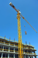 Crane lifting concrete mixer container against blue sky