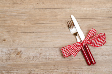 Rustikaler Tisch aus Holz mit Messer und Gabel in rot