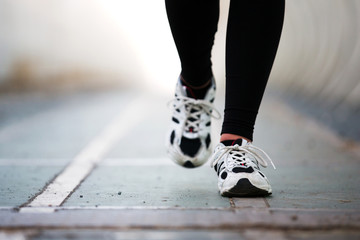 Runner feet walking on road closeup on shoe. woman fitness jog w