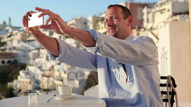 Man taking photo with cellphone in cafe on Santorini