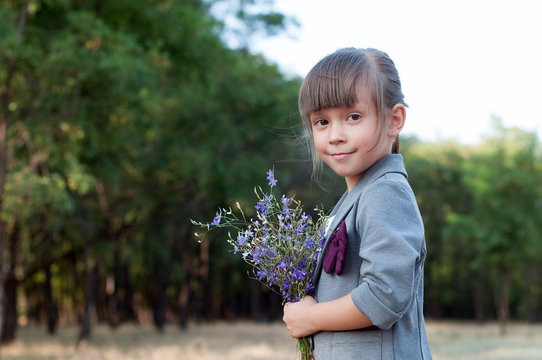 little girl with a bouquet of wildflowers in the park