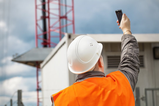 Engineer With The Cell Phone Near To Gsm Tower