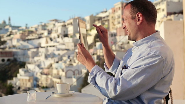 Man taking photo with tablet in cafe on Santorini