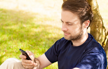 Fototapeta premium Caucasian man looking at mobile phone outdoor