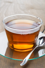 Glass cup of black tea on wooden background, close-up