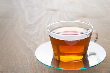 transparent glass cup of black tea on wooden background