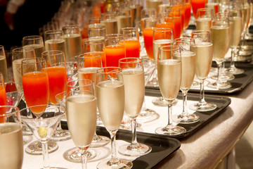 Row of glasses filled with champagne lined up ready to be served