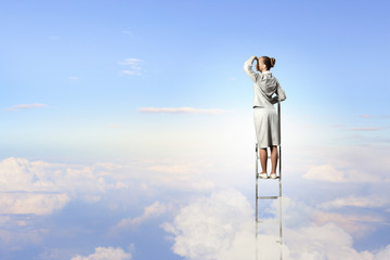 Businesswoman standing on ladder