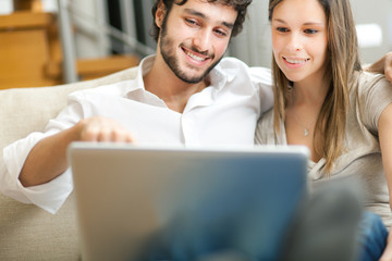 Young couple with their laptop on the couch
