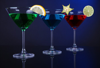 Alcoholic cocktails in martini glasses on dark blue background