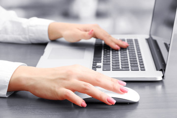 Female hands working on laptop, on grey background