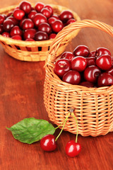 Cherry berries in wicker baskets on wooden table close-up