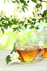 Cup of tea with jasmine, on wooden table, on bright background