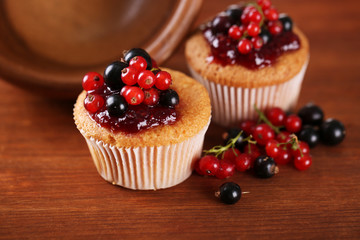Tasty muffins with berries on wooden background