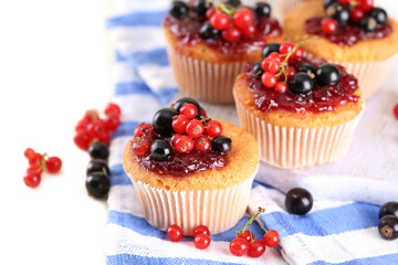 Tasty muffins with berries on white wooden table