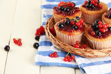 Tasty muffins with berries on white wooden table