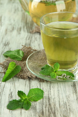 Teapot and cup of herbal tea with fresh mint flowers