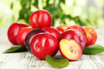 Ripe plums on wooden table on natural background