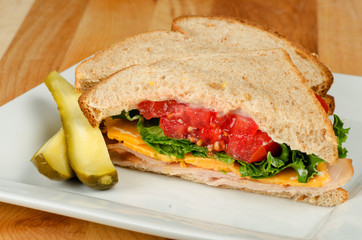 Turkey sandwich with cheese, tomato and lettuce on wheat bread