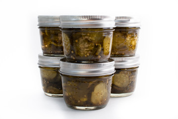 Six jars of pickes stacked on a white isolated background