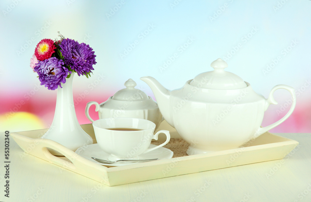 Wall mural Cup of tea with cakes on wooden tray on table in room