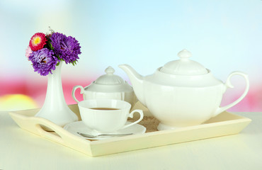 Cup of tea with cakes on wooden tray on table in room