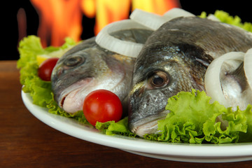 Dorado fish on table on fire background