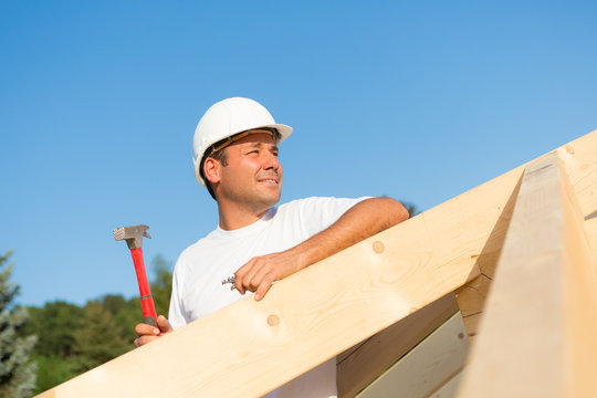 Junger Bauarbeiter am Dachstuhl eines neuen Hauses