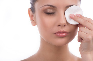 Obraz na płótnie Canvas Removing eye make-up. Beautiful young woman using cotton ball to
