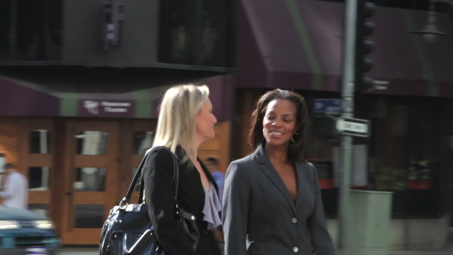 Two Businesswomen Chatting Walking Along Street
