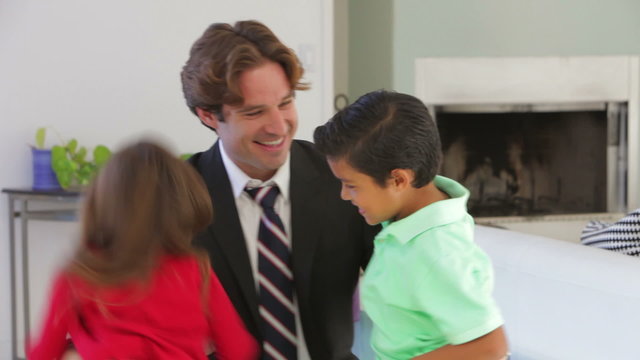 Businessman Home From Work Greeted By Children