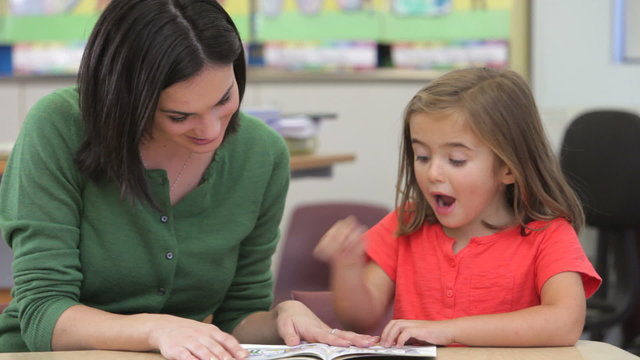Teacher Reading Book With Female Pupil