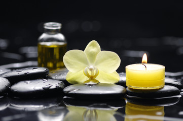 Fototapeta na wymiar Yellow candle with bottle of essential oil and orchid on pebble