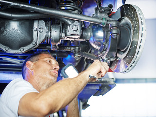 Car mechanic in a garage under a service lift
