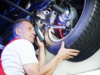 Mechanic in a garage checks a tyre of a car