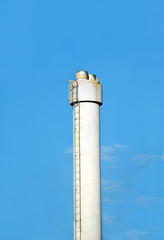 Chimney of industrial plant against blue sky background