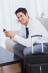 Happy businessman with suitcase and mobile phone