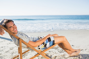 Handsome man lying on his deck chair smiling at camera