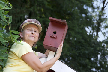 Ältere Frau im Garten beim Vogelhäuschen