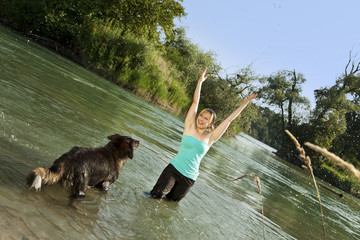 Frau spielt mit Hund im Wasser