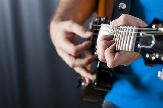 close up shot of strings and guitarist hands playing guitar
