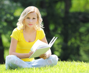 Girl reading book. beautiful blonde with book sitting on grass