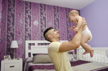 Modern and young father with baby in bedroom.