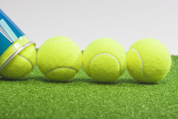 Tennis concepts: four tennis balls close to a container lie on g