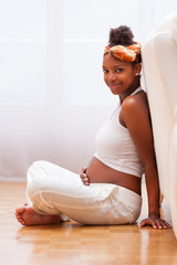 Young pregnant black woman touching her belly - African people