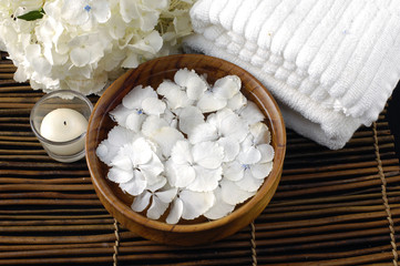 Fototapeta na wymiar Wooden bowl of white hydrangea and towel on mat