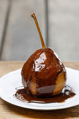 Pear with chocolate on wooden table. Copy space