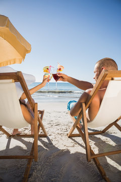 Couple Clinking Their Glasses While Relaxing On Their Deck Chair