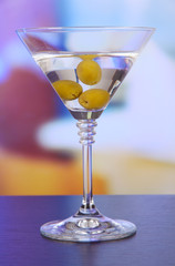 Martini with green olives on table in bar